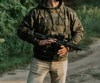 A man wearing the hoodie while holding a machine gun